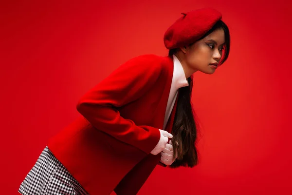 Модна азіатська модель в білих рукавичках регулювання куртки ізольовані на червоному — стокове фото