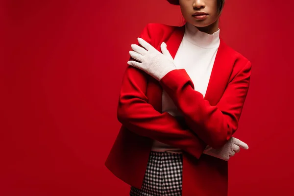 Cropped view of stylish woman in jacket and gloves posing isolated on red — Foto stock