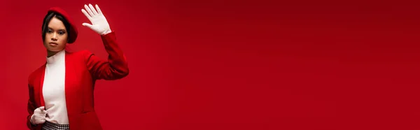 Trendy asian woman in jacket waving hand at camera isolated on red, banner — Foto stock
