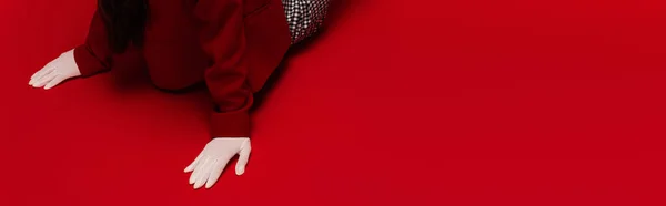 Cropped view of woman in blazer and white gloves sitting on red background, banner — Foto stock