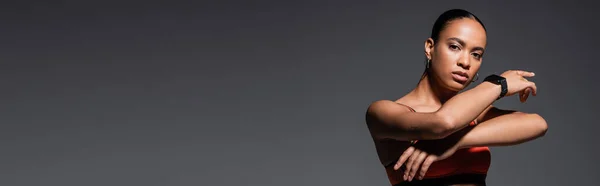 Молода афроамериканська спортсменка з татуюванням позує ізольовано на сірому, банер — стокове фото