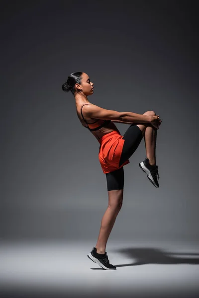 Full length of sportive african american woman in sneakers training on grey — Fotografia de Stock
