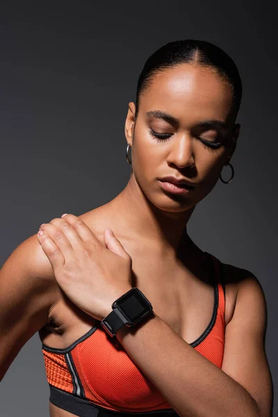 Brunette african american woman with fitness tracker posing isolated on grey — Foto stock