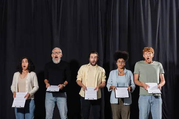 Amazed multicultural actors with bearded art director holding clipboards during rehearsal in acting school — Stock Photo
