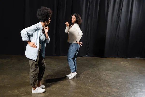 Full length of multiracial woman rehearsing near african american woman on stage in theater — Stock Photo