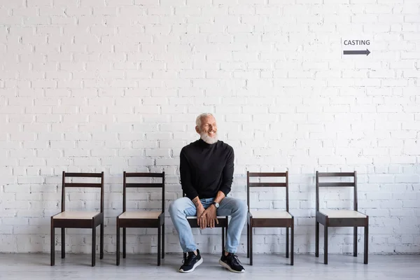 Bearded man smiling with closed eyes while sitting on chair and waiting for casting — Stock Photo