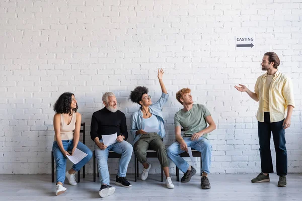 Art director pointing at african american woman raising hand near multiracial actors waiting for casting — Stock Photo
