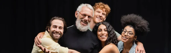 Happy multicultural troupe embracing mature teacher of acting skills and smiling at camera, banner — Stock Photo