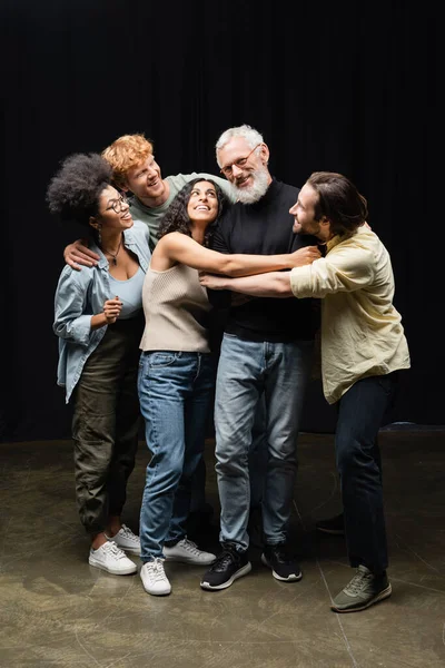 Щасливі мультикультурні студенти обіймають вчителя акторських навичок в театральній школі — стокове фото