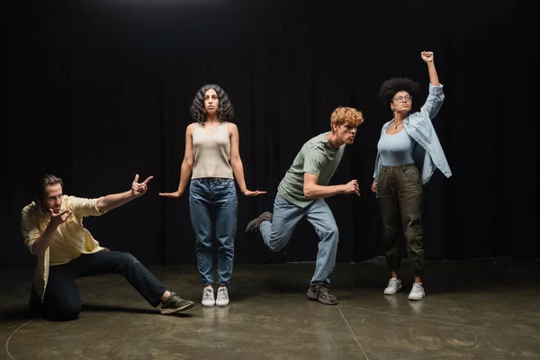 Full length of young multiethnic actors rehearsing in different poses on stage of theater — Fotografia de Stock