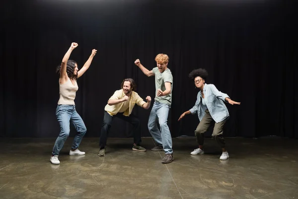 Full length of excited interracial students posing in acting skills studio - foto de stock