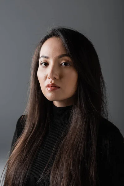 Portrait of pretty and asian woman in black turtleneck looking at camera isolated on dark grey - foto de stock