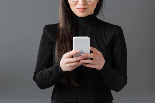 Cropped view of woman in black turtleneck using smartphone isolated on dark grey — стоковое фото