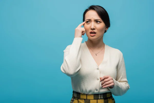 Pensive asian woman looking away isolated on blue — Stock Photo