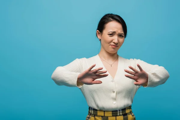 Confused asian woman showing stop gesture isolated on blue — Stockfoto