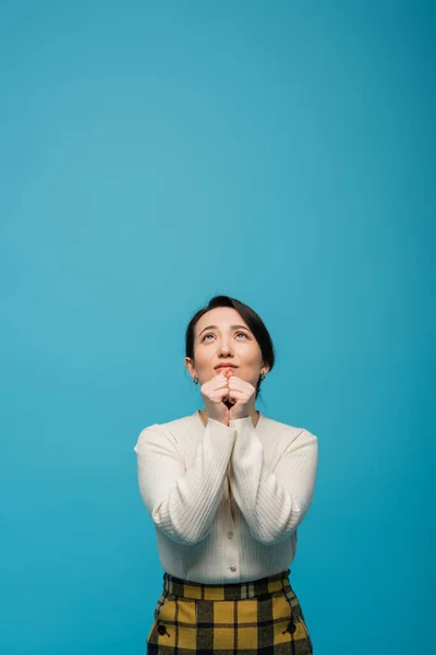 Young asian woman looking up isolated on blue with copy space — Stockfoto