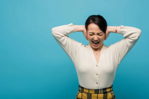 Angry asian woman screaming isolated on blue — Stock Photo