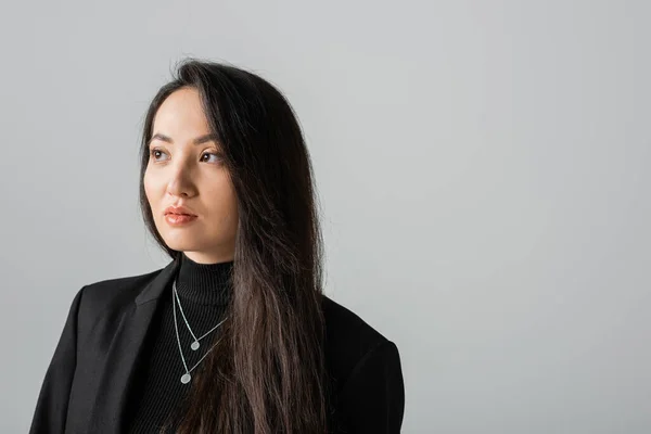 Портрет брюнетки азіатки в чорній куртці дивиться ізольовано на сірому — стокове фото