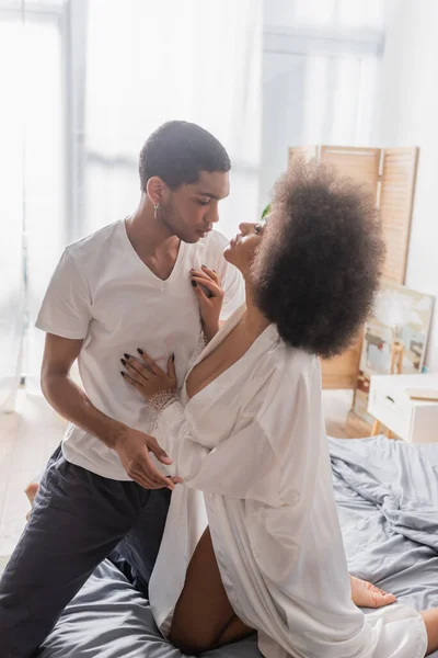 Jovem e apaixonado casal afro-americano olhando uns para os outros na cama em casa — Fotografia de Stock