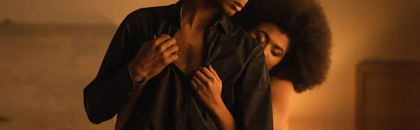 Vue partielle de l'homme en chemise noire près de frisée femme afro-américaine avec les yeux fermés, bannière — Photo de stock