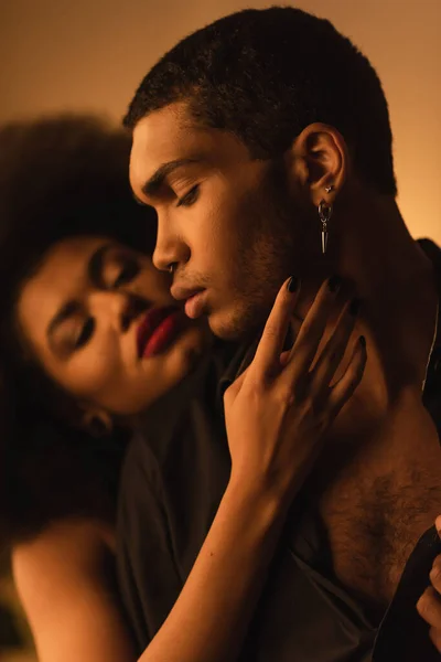 Passionate african american woman touching face of young boyfriend at home at night — Foto stock