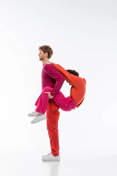Side view of multiethnic couple in magenta color clothes showing p letter on white background — Stock Photo