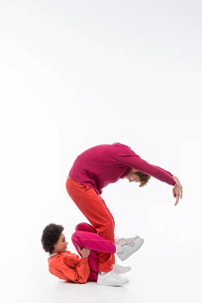 Side view of multiethnic couple in magenta color clothes showing s letter on white background — Stock Photo