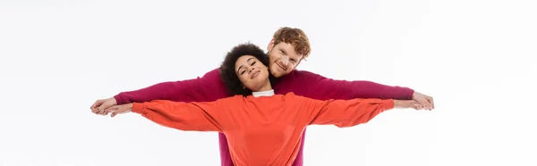 Happy and interracial couple in magenta color clothes holding hands on white background, banner — Stock Photo