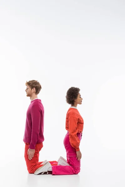 Side view of interracial couple in magenta color clothes showing u letter on white background — Stock Photo