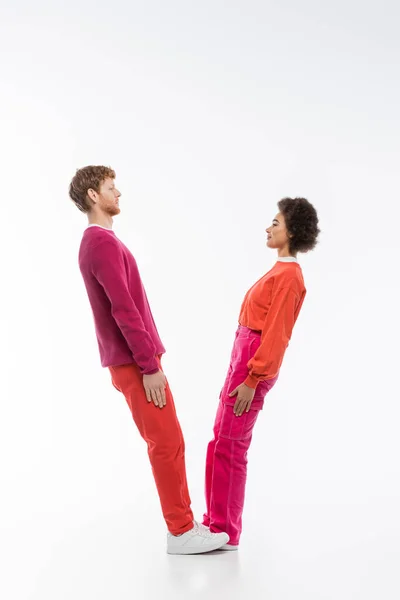 Side view of interracial couple in magenta color clothes showing v letter on white background — Stock Photo