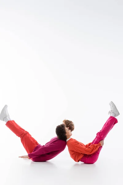 Side view of interracial couple in magenta color clothes showing w letter on white background — Stock Photo