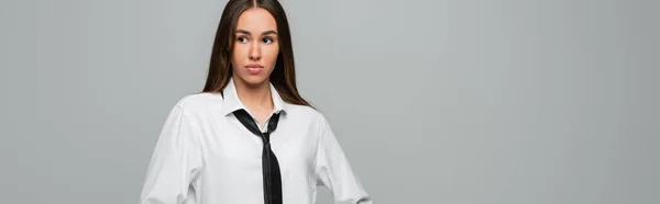 Brunette femme en chemise blanche et cravate regardant loin isolé sur gris, bannière — Photo de stock