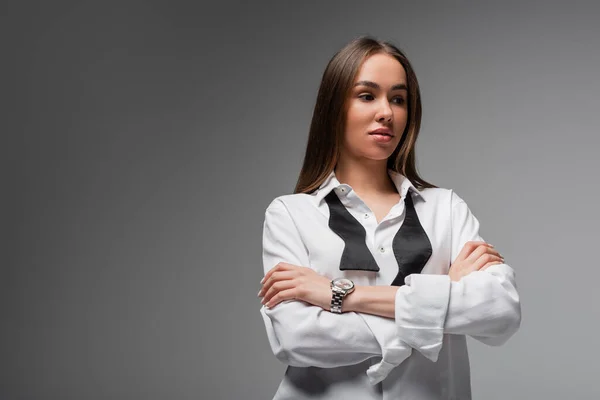 Портрет впевненої жінки в білій сорочці та чорній краватці, що стоїть з схрещеними руками ізольовано на сірій концепції гендерної рівності — стокове фото