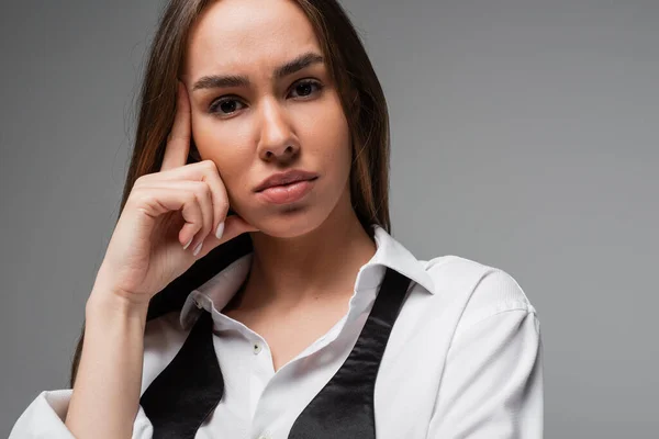 Portrait of brunette woman in white shirt and black tie looking at camera isolated on grey — Stock Photo