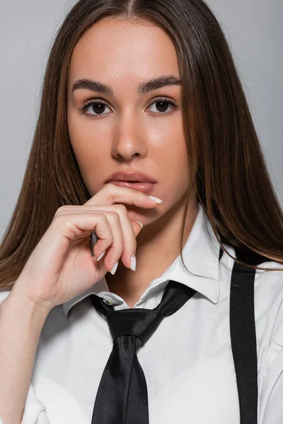 Portrait of young brunette woman with long hair looking at camera isolated on grey — Stock Photo