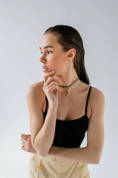Thoughtful model in beige pants and black top looking away isolated on grey — Stock Photo