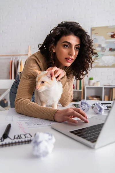 Copywriter using laptop near oriental cat and papers at home — Stock Photo