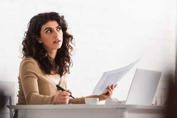 Pensive copywriter working with papers and laptop at home — Stock Photo