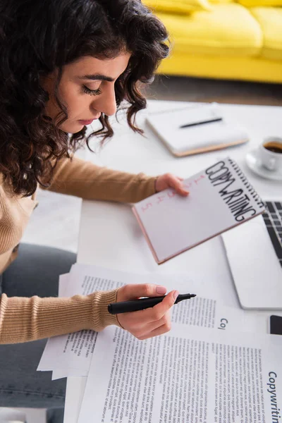 Young copywriter holding marker near papers and notebook at home — Stock Photo