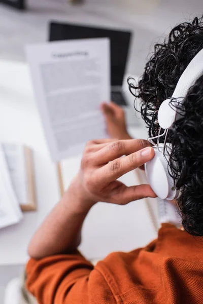 Back view of indian freelancer in headphones working with papers at home — Stock Photo
