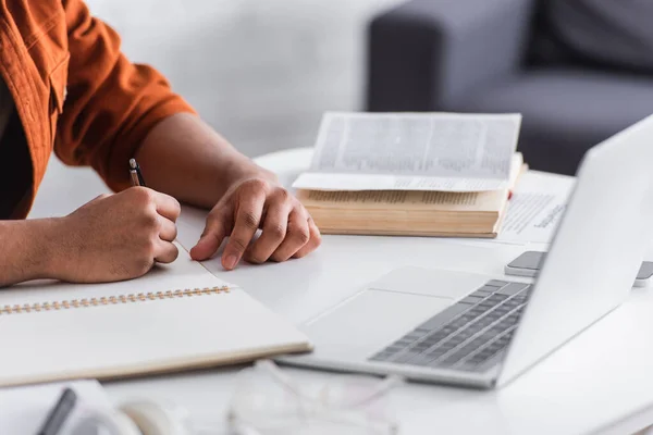 Cropped view of copywriter writing on notebook near devices at home — Stock Photo