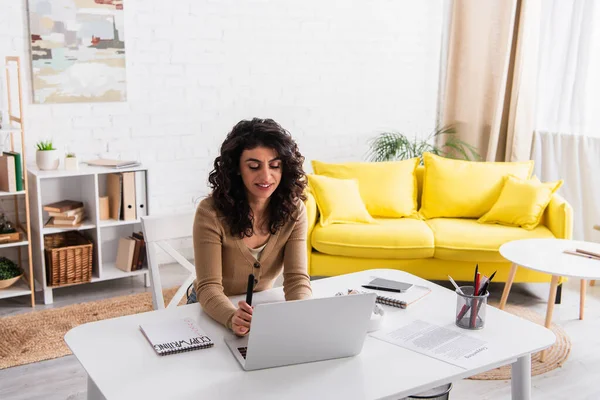 Smiling copywriter using laptop near papers and notebooks at home — Stock Photo