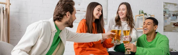 Весёлые межрасовые друзья звенят стаканами пива в гостиной, баннером — стоковое фото