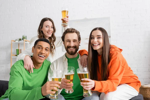 Щаслива міжрасова група друзів тримає келихи пива у вітальні — стокове фото