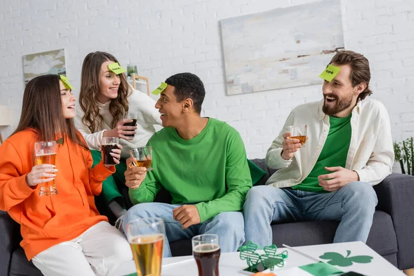 Alegre interracial amigos com bebidas jogar quem eu sou jogo enquanto celebrando santo patrick dia — Fotografia de Stock