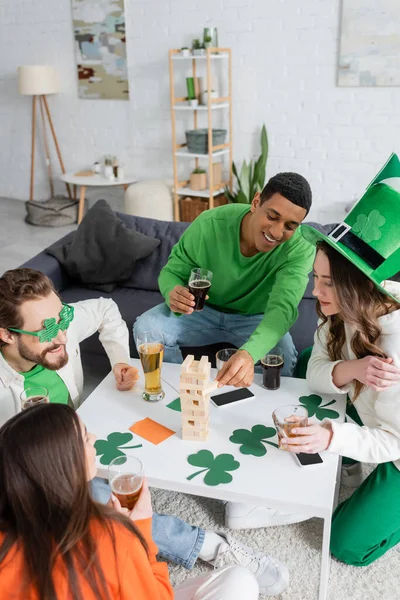 African american man playing wood blocks game with friends during saint patrick day celebration — Stock Photo