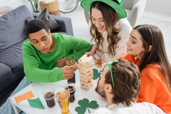 High angle view of african american man playing wood blocks game near friends and beer at home — Stock Photo
