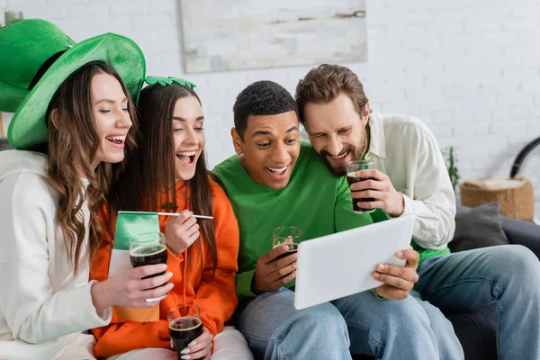 Positive multiethnic friends with beer using digital tablet at home — Photo de stock