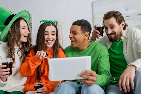 Multiethnic friends with beer using digital tablet during saint patrick day at home — Photo de stock