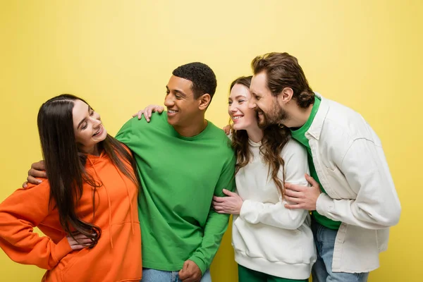 Smiling multiethnic friends looking at young woman on yellow background — Stock Photo